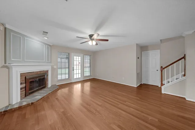 a view of an empty room with wooden floor fireplace and a window