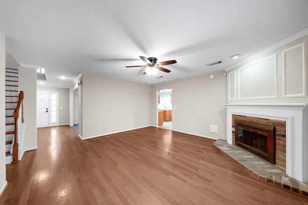 a view of an empty room with wooden floor fireplace and a window