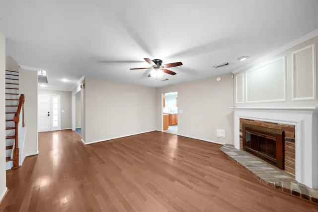 a view of an empty room with wooden floor fireplace and a window