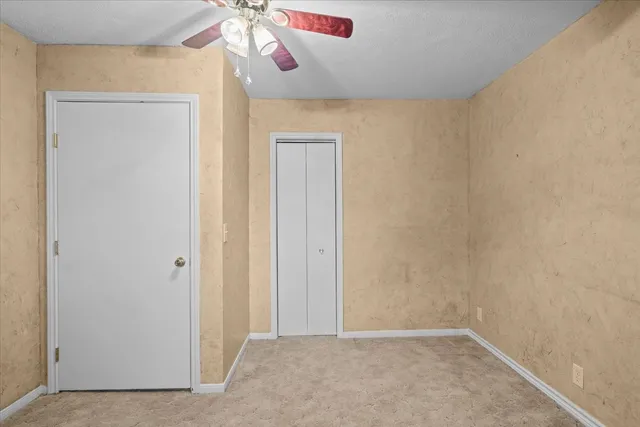 a bedroom with a bed a table and large windows