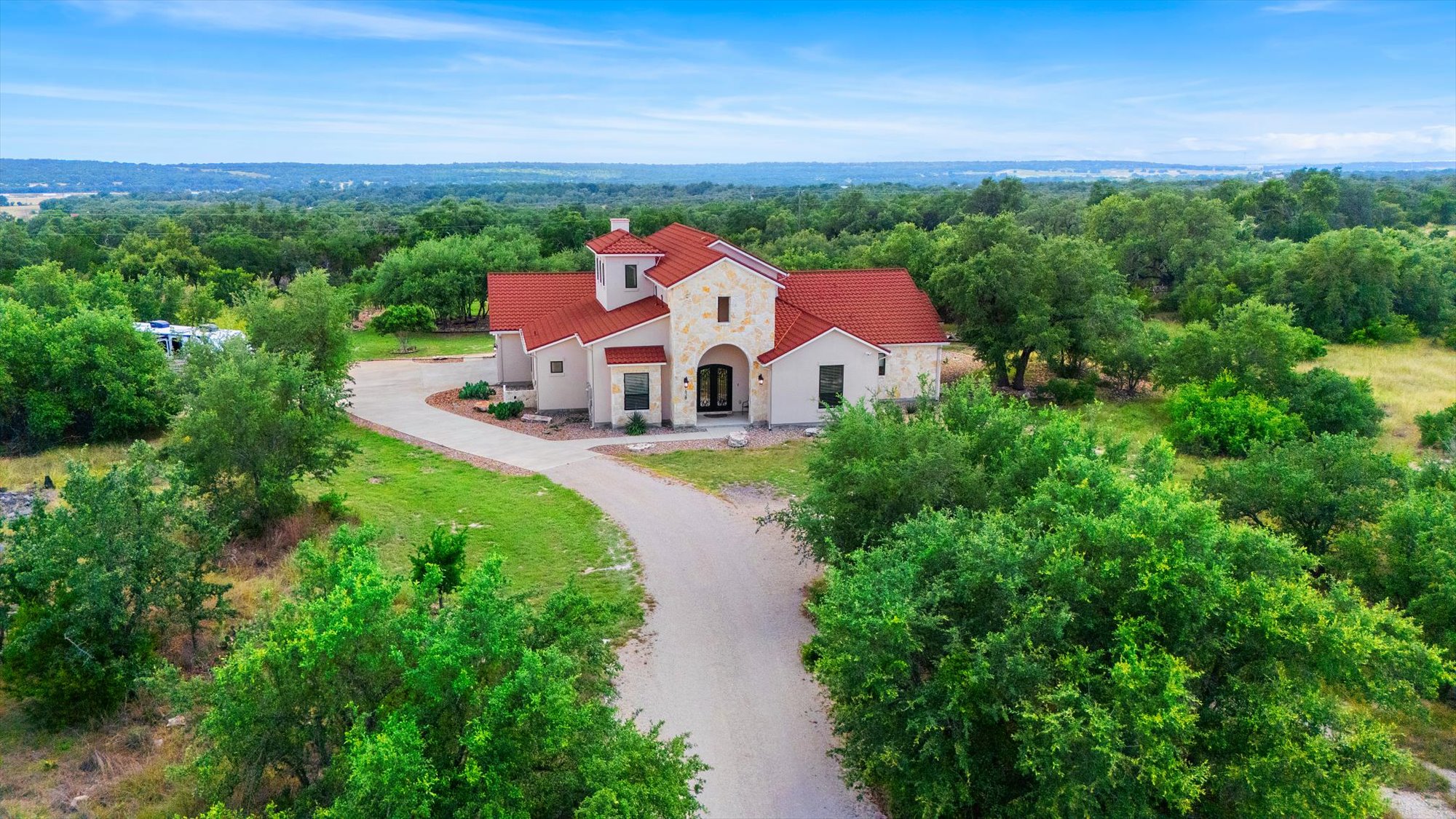 638 Strada Luca Florence, TX 76527 - Photo 4 of 38 A terracotta-roofed residence nestled amongst verdant trees, offering expansive views of the surrounding landscape.