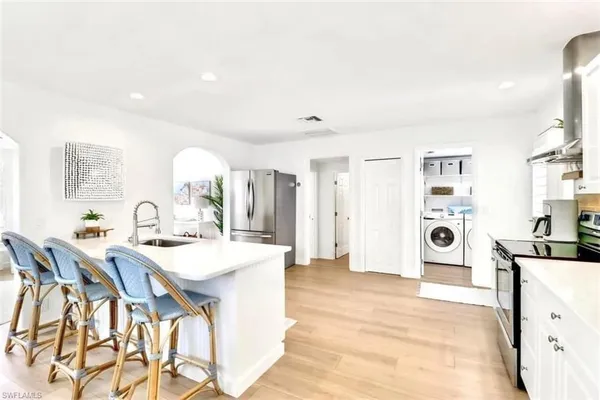 a large white kitchen with a refrigerator a stove a sink dishwasher with a dining table and chairs