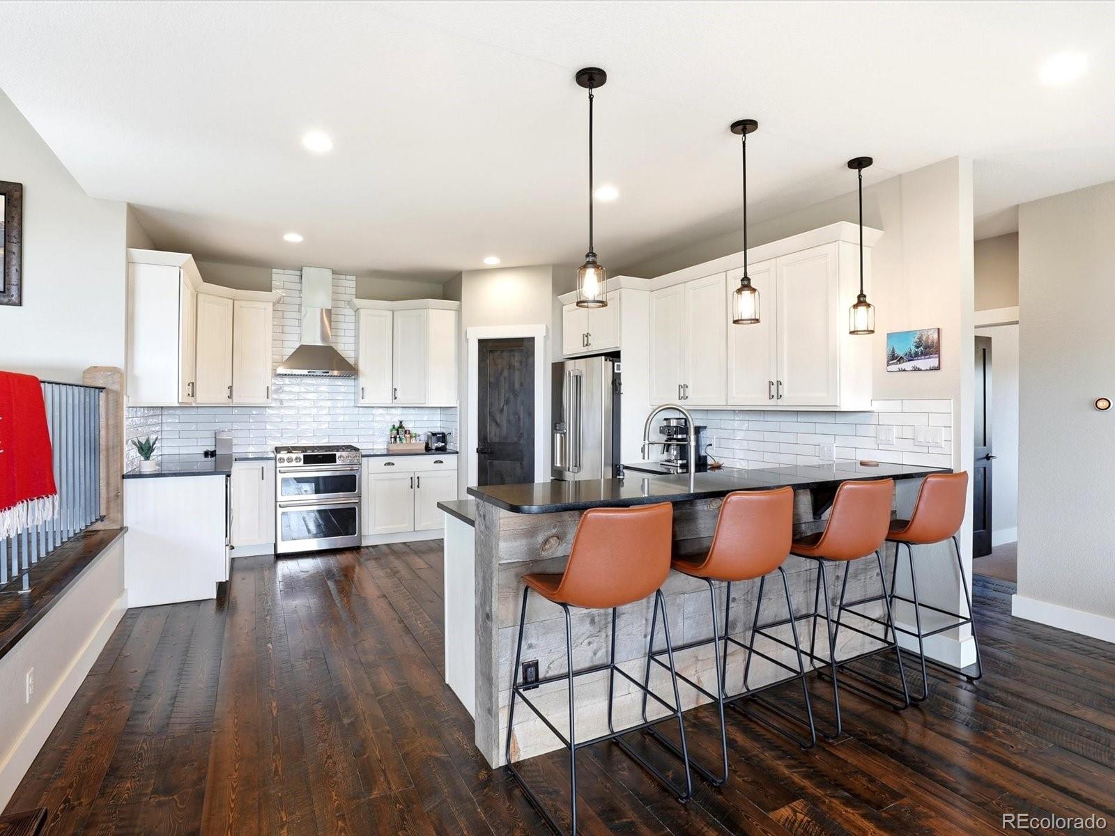 7333 Plowsher Way Morrison, CO 80465 - Photo 9 of 36 a open kitchen with stainless steel appliances granite countertop a stove a refrigerator a kitchen island a dining table and chairs with wooden floor