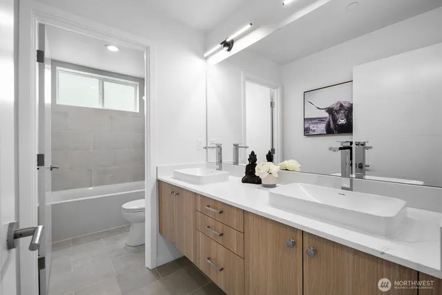 a bathroom with a double vanity sink toilet mirror and bathtub