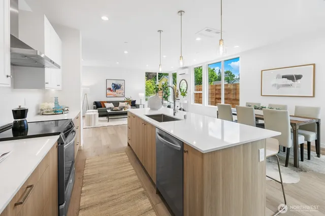 a kitchen with stainless steel appliances granite countertop a sink a stove a refrigerator a dining table and chairs with wooden floor