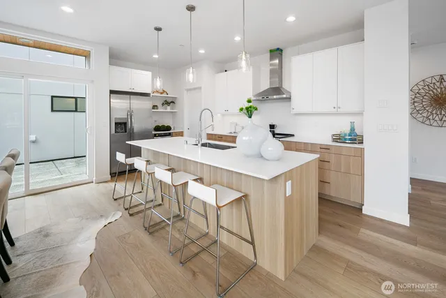 a kitchen with stainless steel appliances kitchen island granite countertop a table chairs and a refrigerator