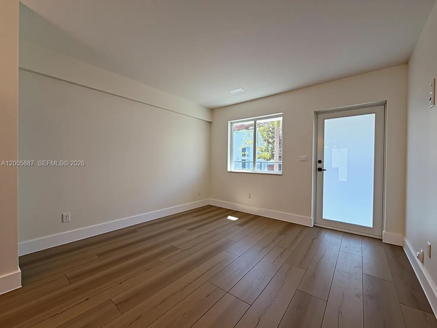 1904 Southwest 17th Avenue, Unit 8 Miami, FL 33145 - Photo 2 of 11 an empty room with wooden floor and windows