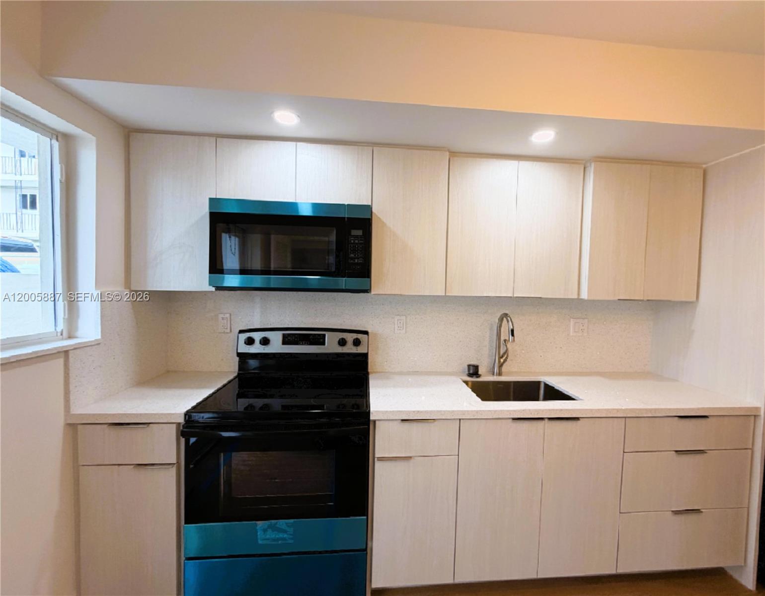 1904 Southwest 17th Avenue, Unit 8 Miami, FL 33145 - Photo 3 of 11 a kitchen with white cabinets and black appliances