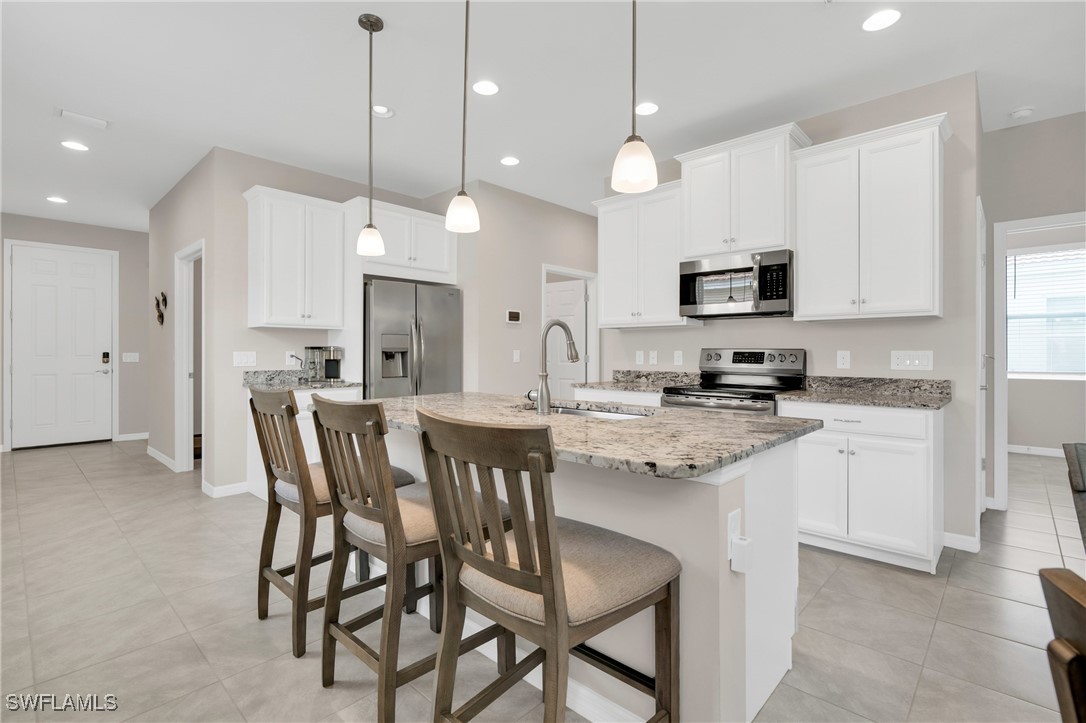 2125 Summersweet Drive Alva, FL 33920 - Photo 13 of 32 a kitchen with stainless steel appliances kitchen island granite countertop a sink a stove a kitchen island with a dining table and chairs