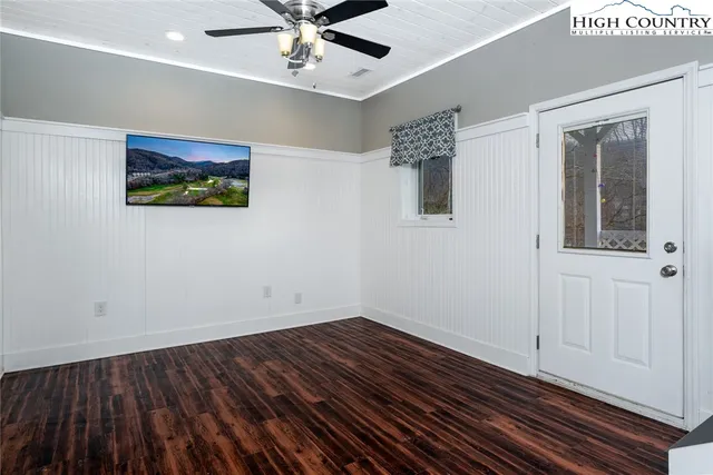 a view of an empty room with wooden floor and a ceiling fan