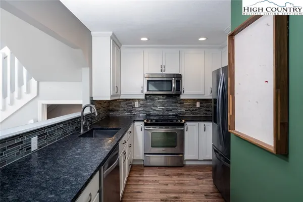 a kitchen with stainless steel appliances granite countertop a stove a refrigerator and a sink