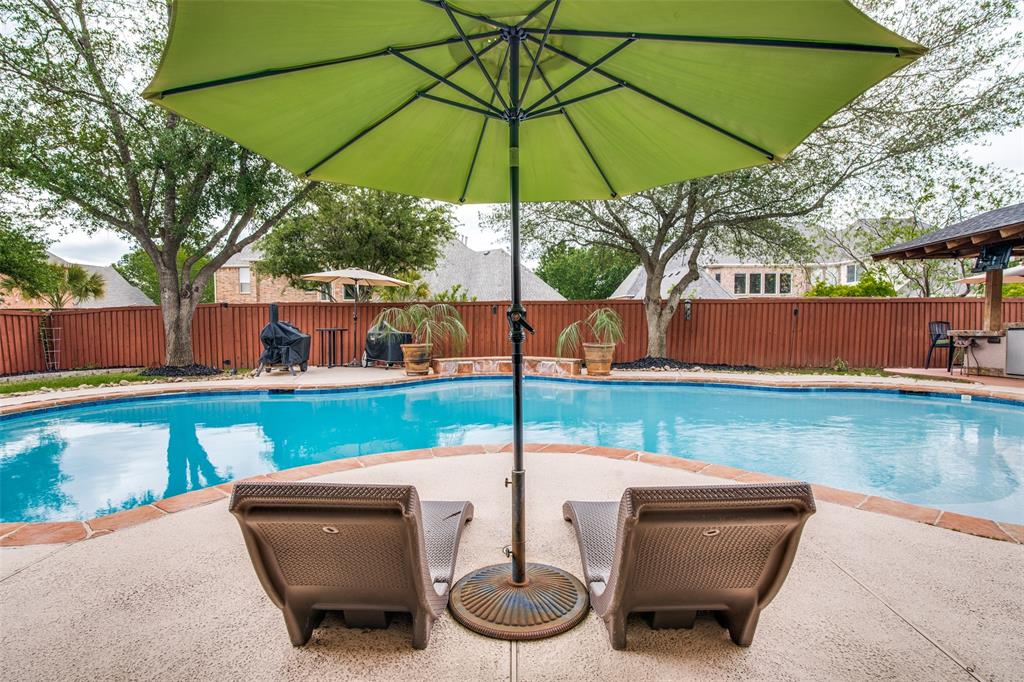 a backyard of a house with table and chairs under an umbrella