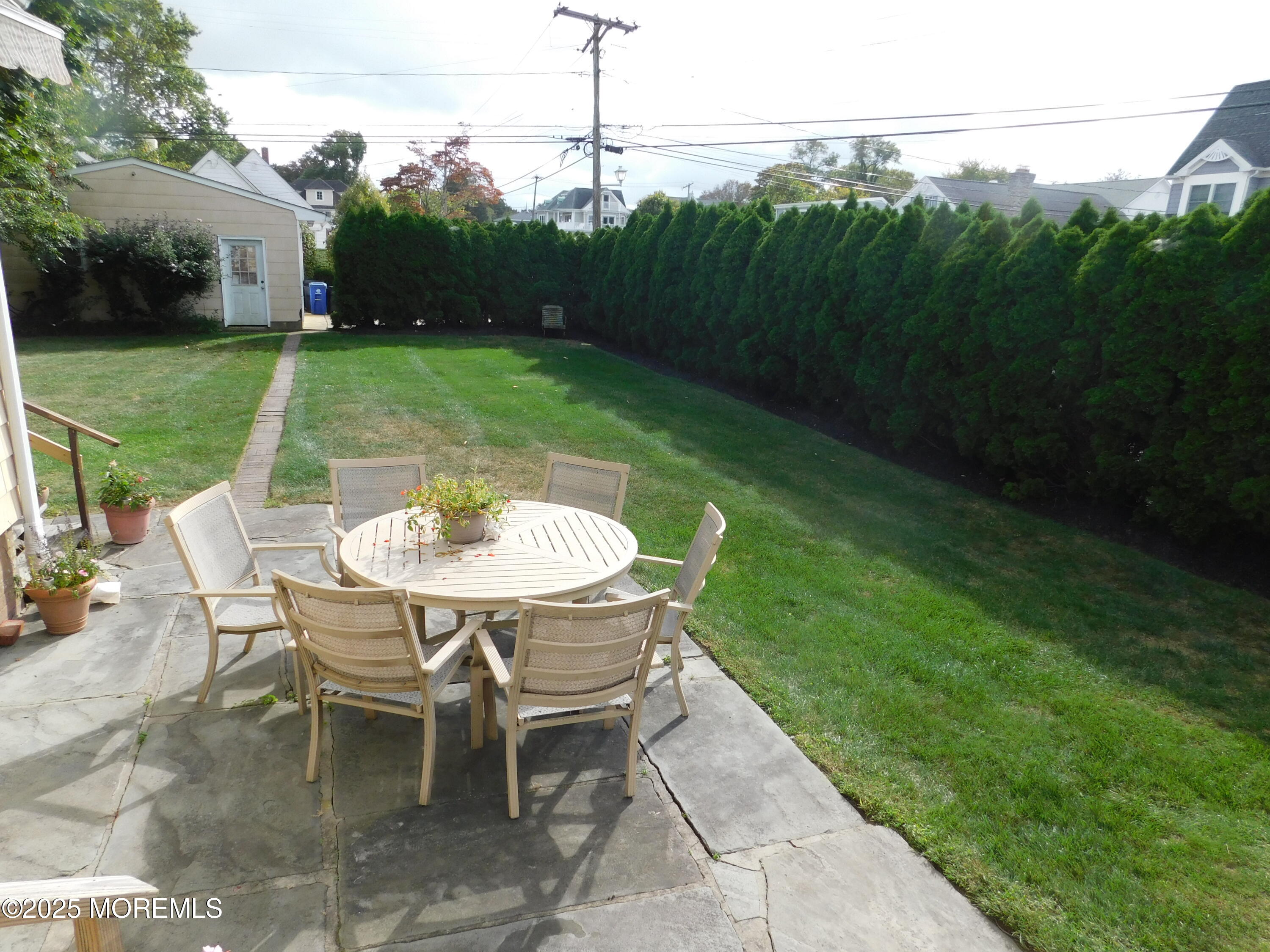 319 Jersey Avenue Spring Lake, NJ 07762 - Photo 19 of 21 a backyard with table and chairs with wooden fence