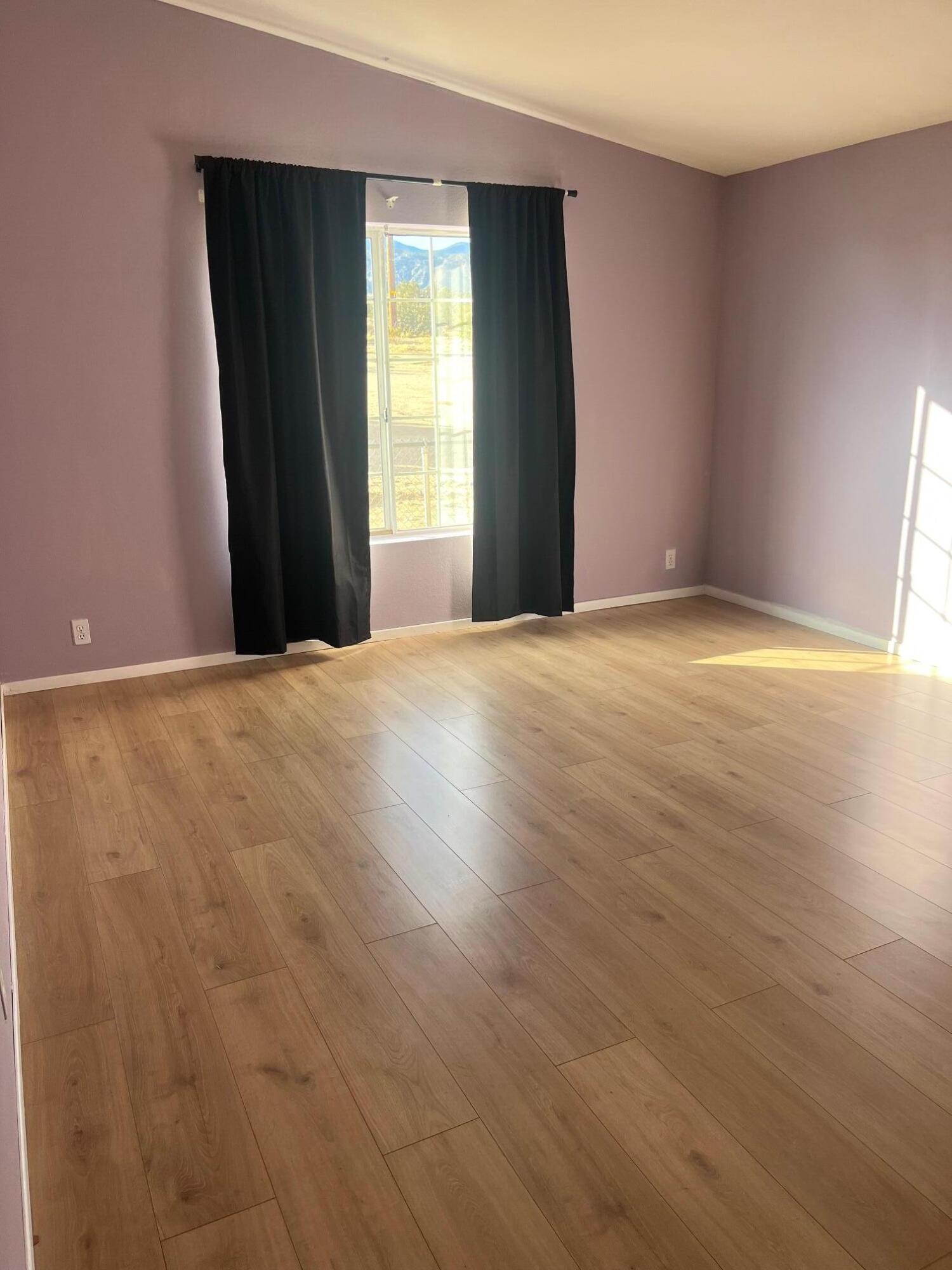 21925 Fort Tejon Road Llano, CA 93544 - Photo 4 of 10 a view of an empty room with wooden floor and a window