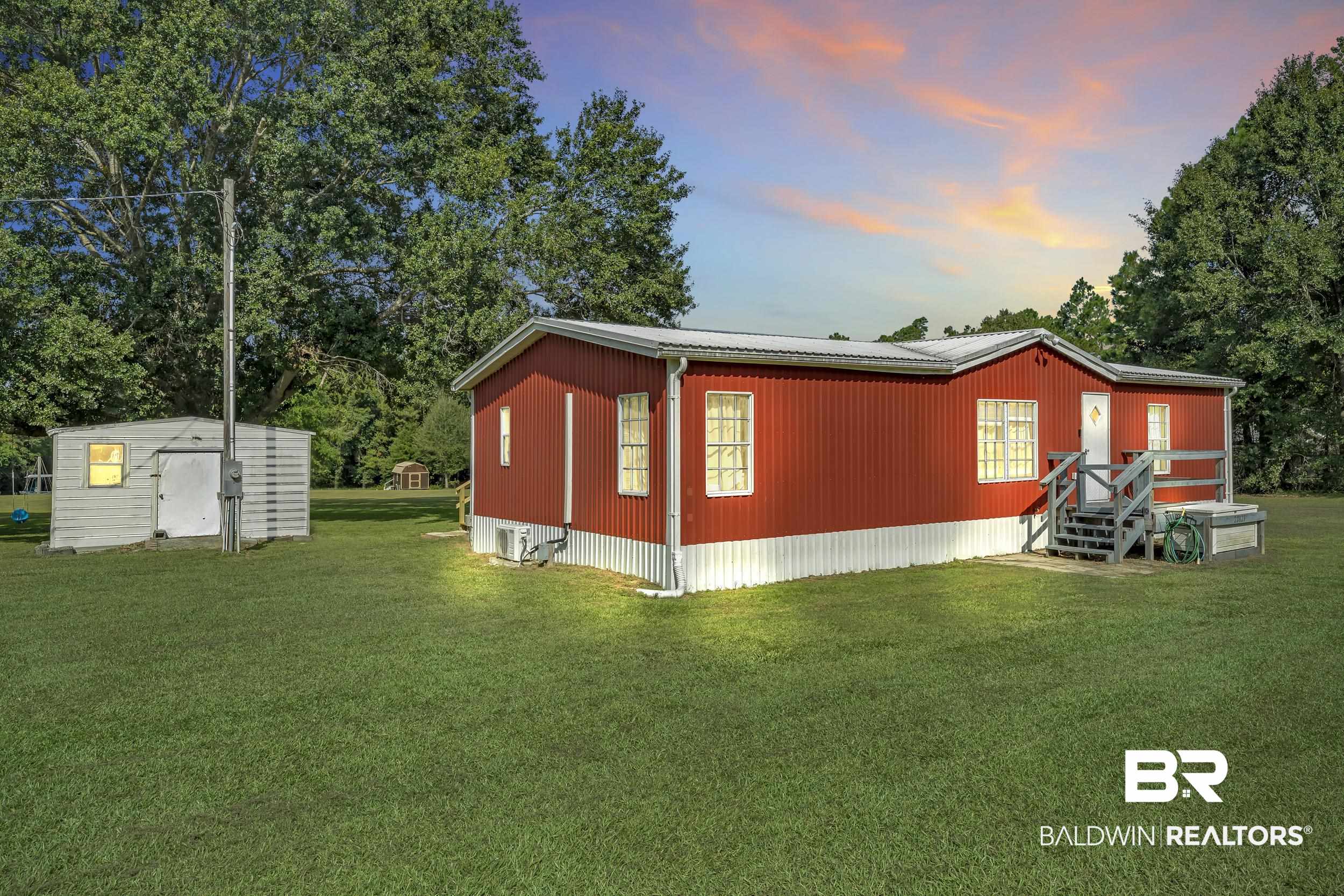22823 Lanier Road Robertsdale, AL 36567 - Photo 4 of 46 View of property exterior with a yard, a storage unit, and a metal roof
