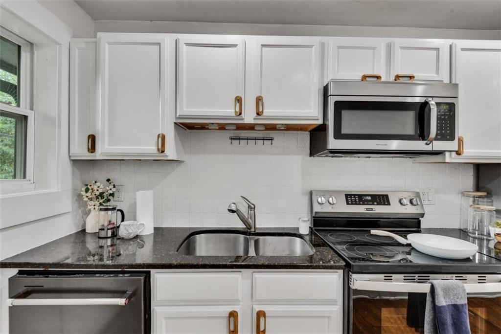 351 Cherokee Avenue Southeast, Unit 8 Atlanta, GA 30312 - Photo 10 of 28 a kitchen with granite countertop a stove a microwave a sink and cabinets