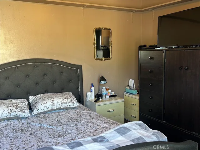 a bedroom with a bed and a flat tv screen on dresser