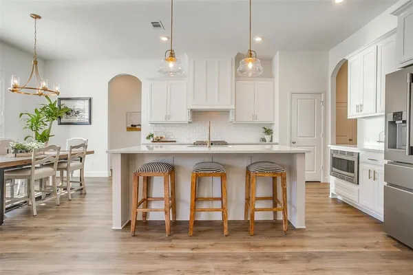 a kitchen with stainless steel appliances granite countertop a table chairs stove a sink and dishwasher