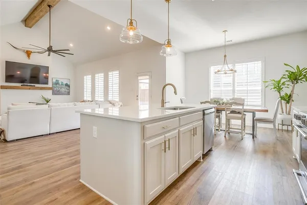 a spacious bedroom with a bed a dresser and flowerpot