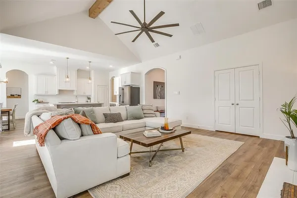 a living room with couches and kitchen view with a large window