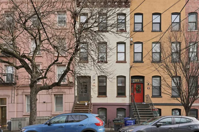 a front view of a building with lot of cars and trees