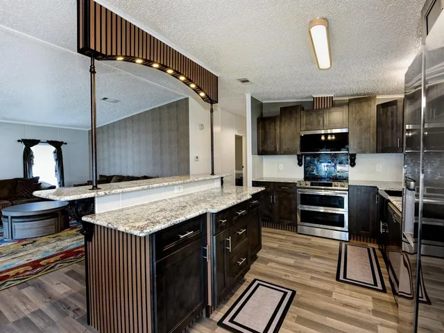 a kitchen with stainless steel appliances granite countertop a stove top oven a sink and a refrigerator