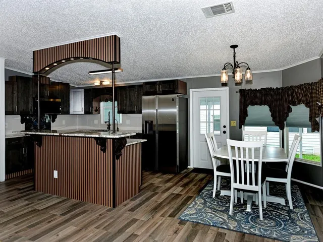 a kitchen with stainless steel appliances granite countertop a dining table chairs and a refrigerator