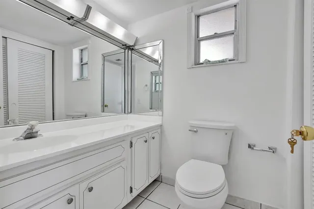 a bathroom with a granite countertop toilet sink and mirror