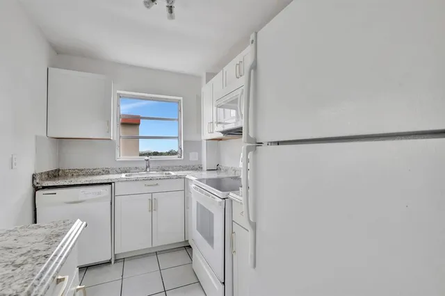 a kitchen with white cabinets and white appliances