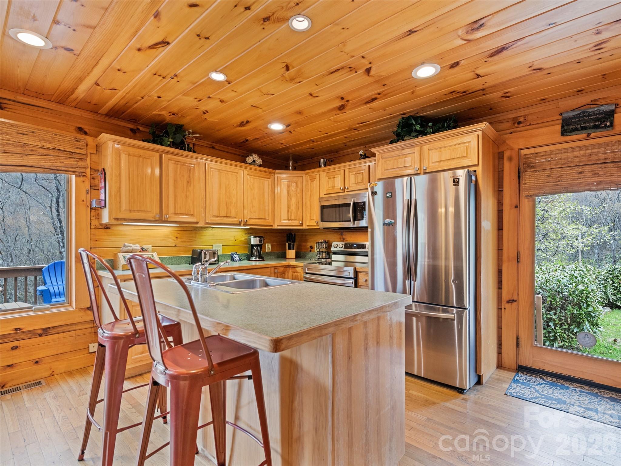 91 Copper Spur Road Maggie Valley, NC 28751 - Photo 8 of 29 a kitchen with stainless steel appliances granite countertop a refrigerator a sink dishwasher a dining table and chairs with wooden floor