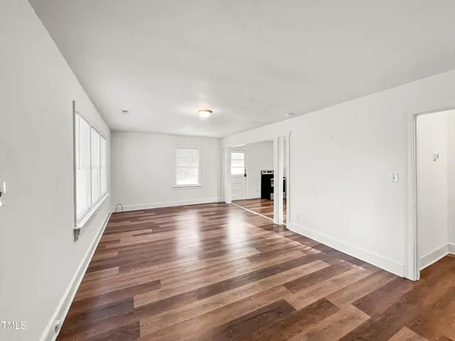 a view of empty room with wooden floor and window