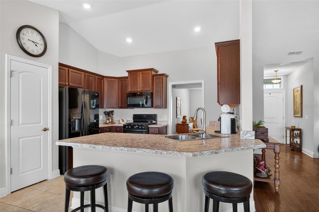 2429 Twin Lake View Road Winter Haven, FL 33881 - Photo 8 of 37 a kitchen with granite countertop a table chairs stove a refrigerator and cabinets