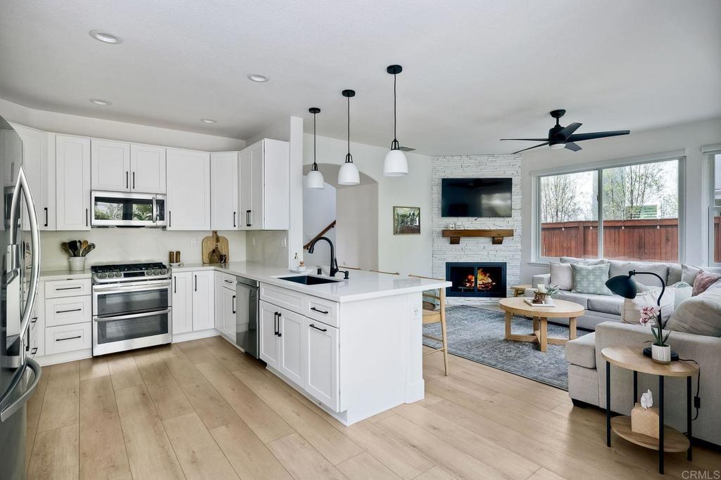 1054 Lighthouse Road Carlsbad, CA 92011 - Photo 11 of 44 a kitchen with stainless steel appliances kitchen island wooden floors and white cabinets