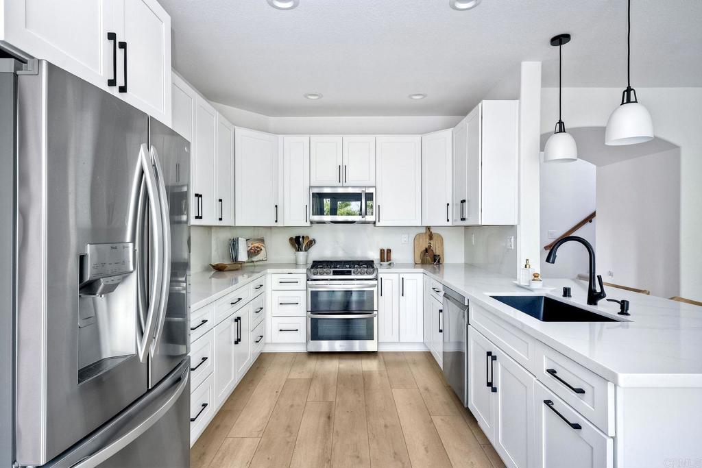 1054 Lighthouse Road Carlsbad, CA 92011 - Photo 9 of 44 a kitchen with white cabinets and stainless steel appliances