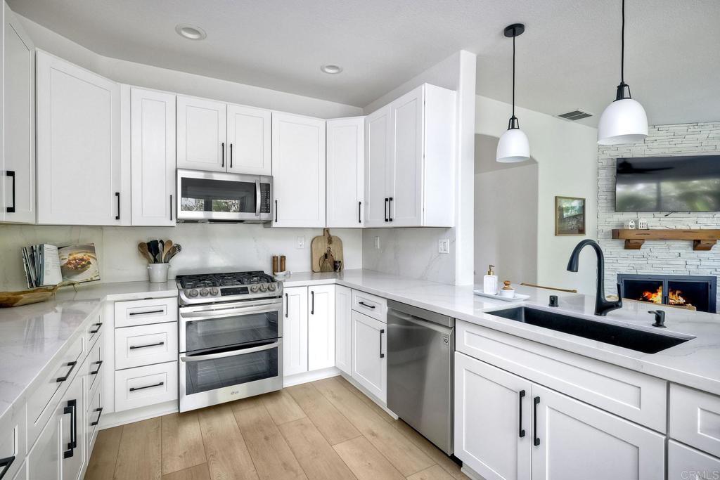 1054 Lighthouse Road Carlsbad, CA 92011 - Photo 10 of 44 a kitchen with stainless steel appliances white cabinets a sink a stove a microwave and wooden floors