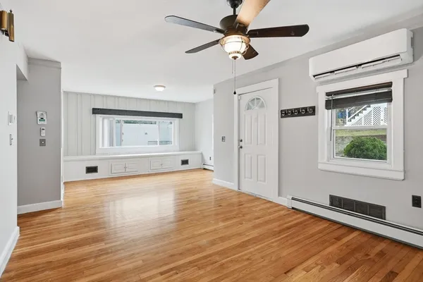 a view of an empty room with window and wooden floor