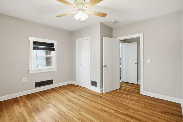 a view of empty room with wooden floor and fan