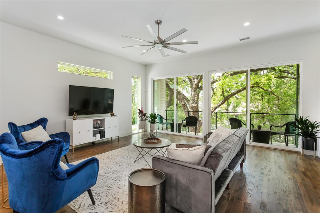 a living room with furniture floor to ceiling window hardwood floor and a flat screen tv