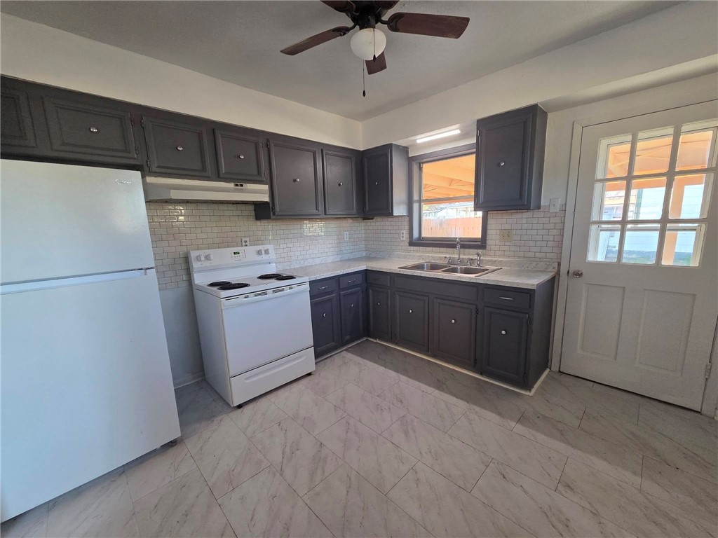 709 East Caesar Avenue Kingsville, TX 78363 - Photo 9 of 15 a kitchen with stainless steel appliances granite countertop a refrigerator a sink dishwasher a stove and white countertops with wooden floor