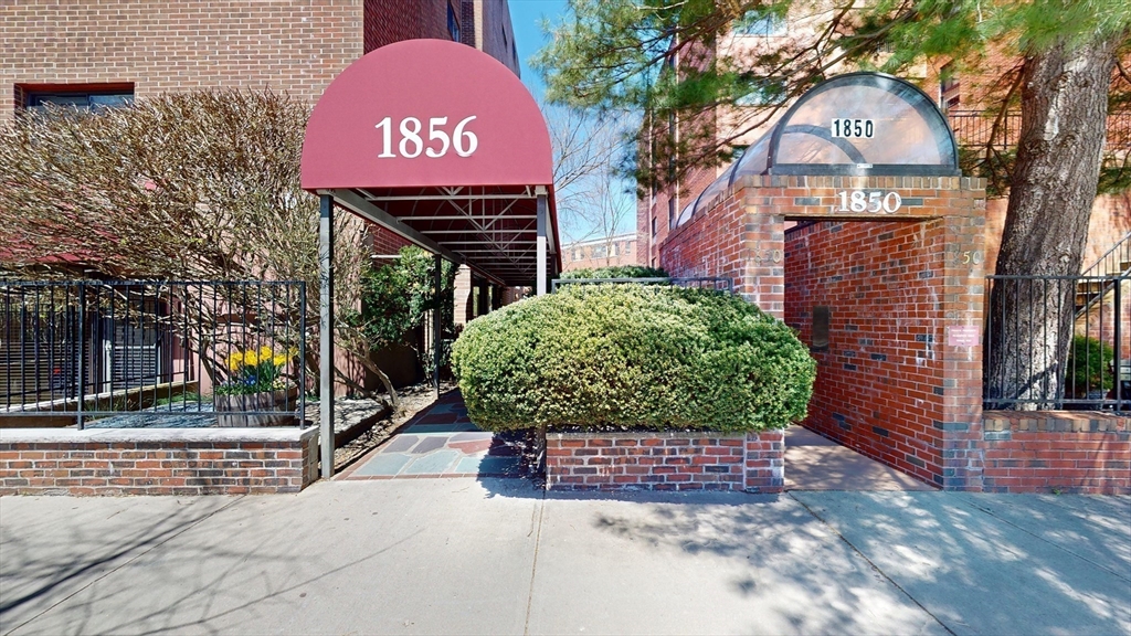 1856 Beacon Street, Unit 6F Brookline, MA 02445 - Photo 16 of 17 a sign board with a small yard and large trees