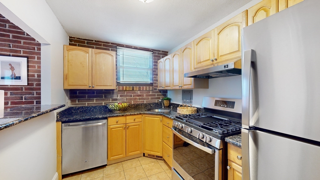 1856 Beacon Street, Unit 6F Brookline, MA 02445 - Photo 4 of 17 a kitchen with stainless steel appliances granite countertop a stove a sink and a microwave