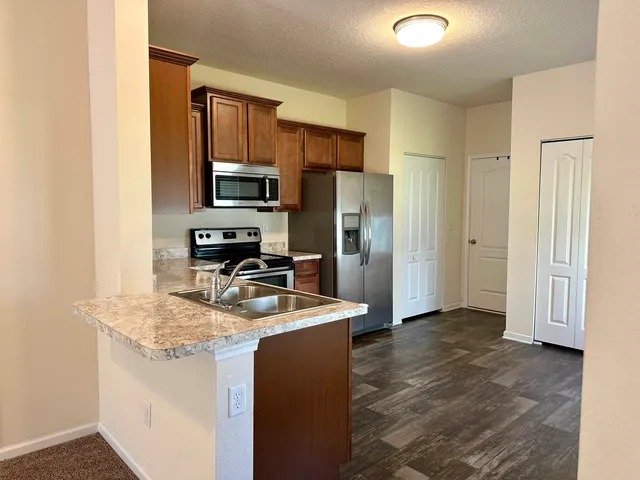 a kitchen with granite countertop a refrigerator and a stove top oven