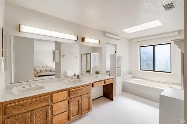 a spacious bathroom with a double vanity sink a mirror and a bathtub