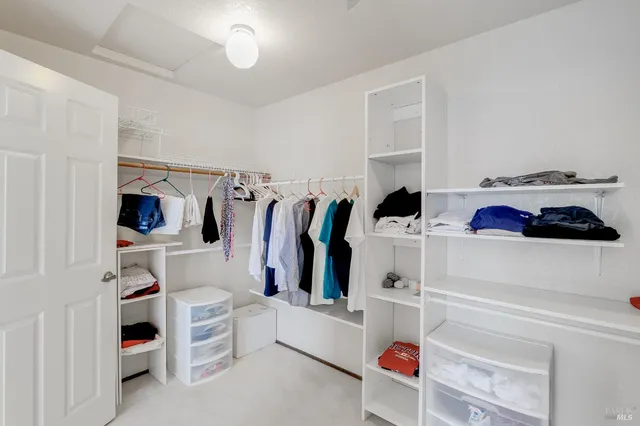a view of walk in closet with clothes and shoes