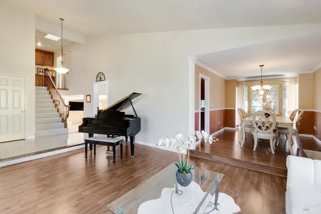 a dining room with wooden floor a chandelier a glass table and chairs