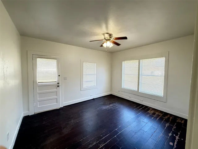 a view of an empty room with a window and wooden floor