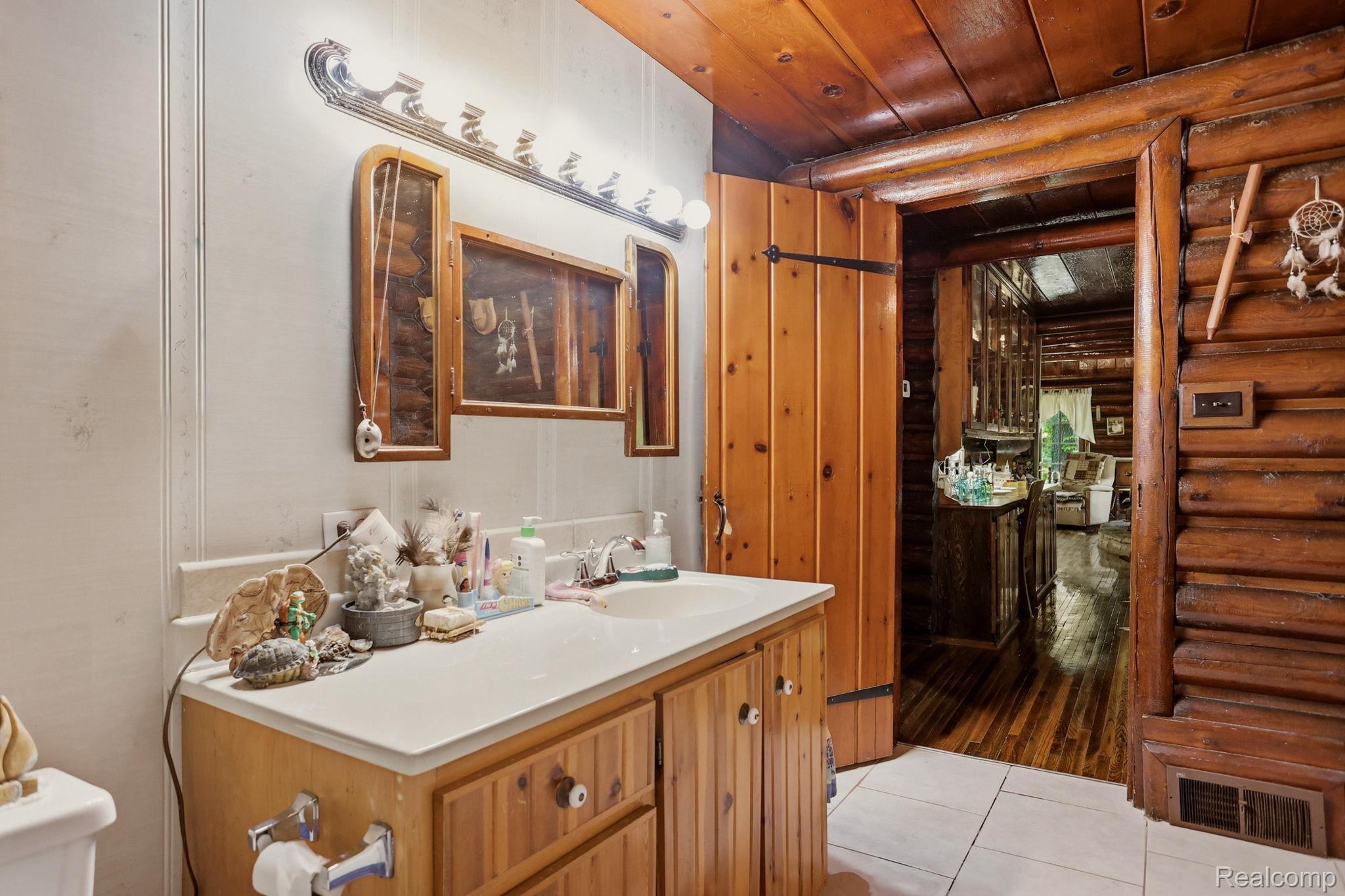 3814 South Towerline Road Bridgeport, MI 48722 - Photo 27 of 52 Bathroom featuring a wood vanity with integrated sink, a large wall-mounted mirror, and tile flooring
