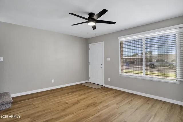 a view of an empty room with wooden floor and a window