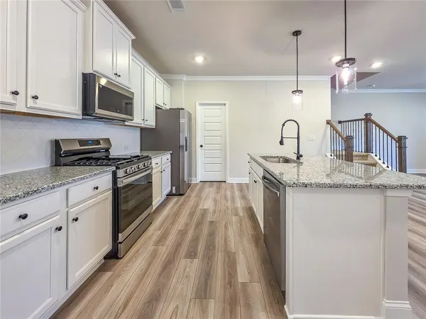 a kitchen with stainless steel appliances granite countertop a sink a stove and a wooden floors