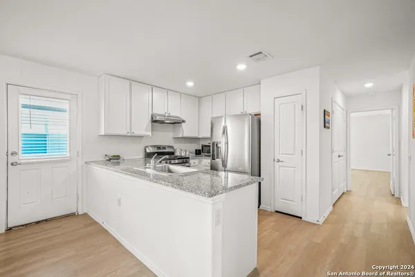 a kitchen with stainless steel appliances granite countertop a sink refrigerator and cabinets